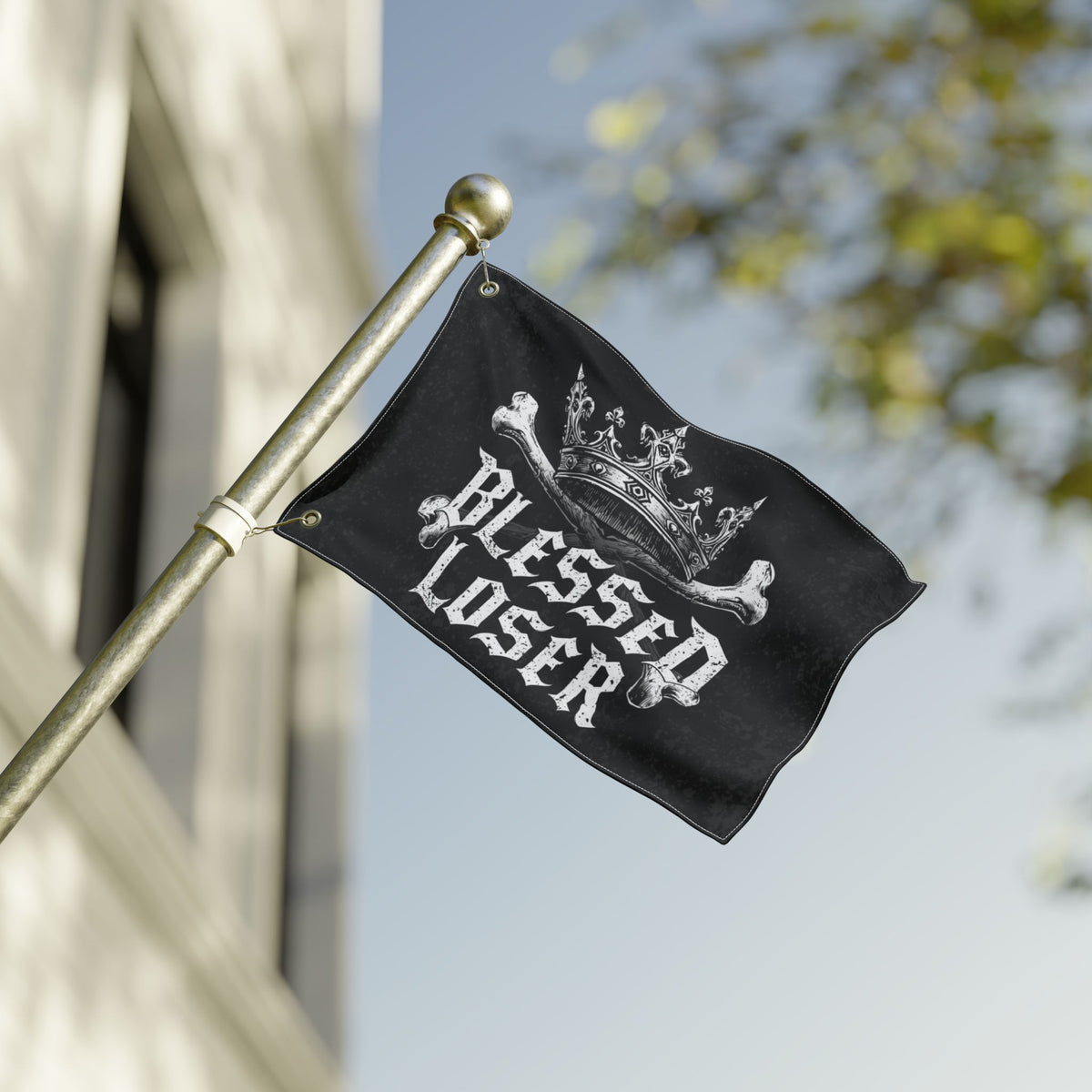 Blessed loser Black flag waving on a flagpole, showcasing its unique design against a clear sky.