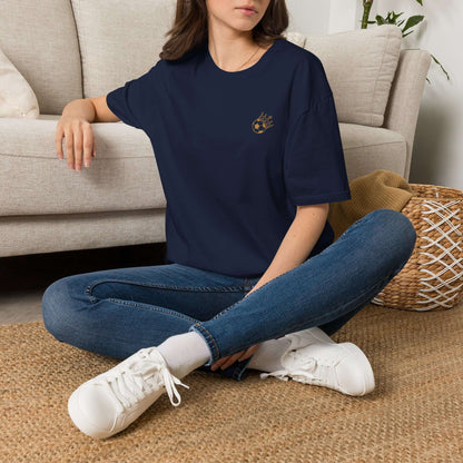 Cute Crowned Cat Pocket Tee — Minimal Embroidered Kitten T-Shirt modeled by a woman sitting on a floor, wearing jeans and sneakers.